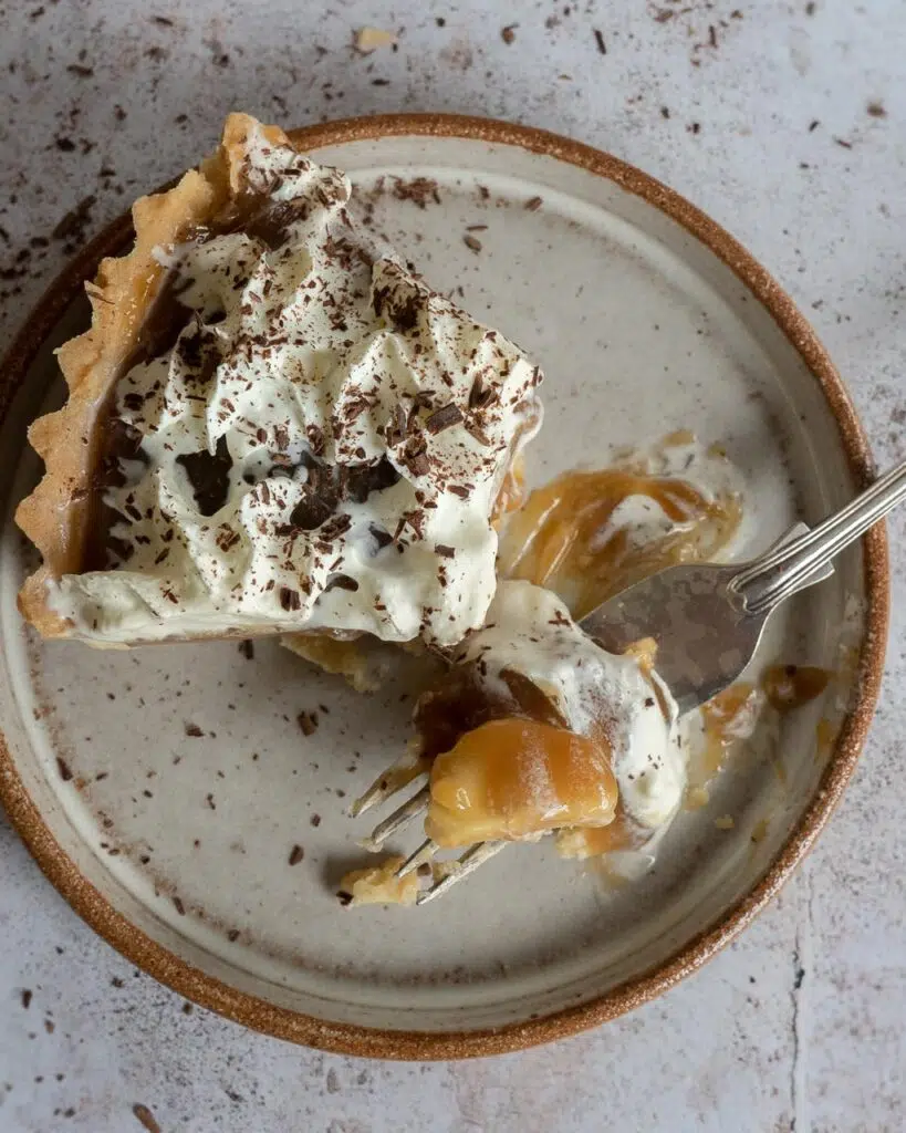 A slice of vegan Banoffee Pie with caramel and whipped cream spread across the plate