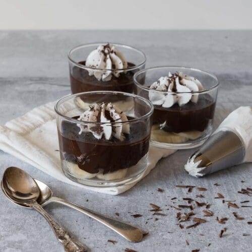 3 glass dishes of easy avocado chocolate pudding with whipped coconut cream and grated chocolate on top