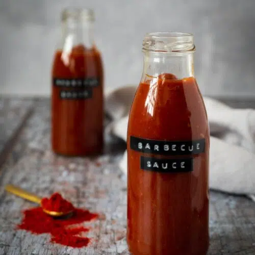 Two glass bottles filled with rich red homemade bbq sauce