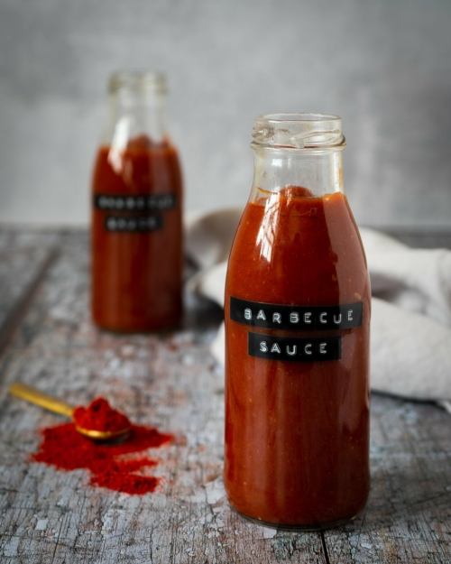 Two glass bottles filled with rich red homemade bbq sauce