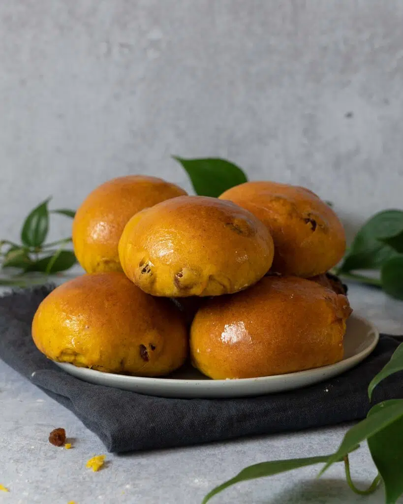 A plate of glossy golden yellow saffron buns studded with juicy sultanas