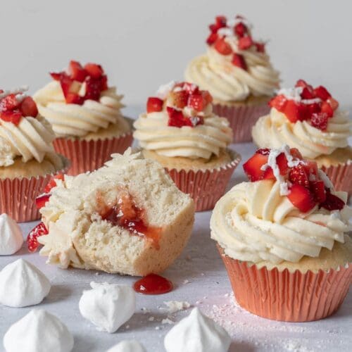 Pretty Eton Mess Cupcakes with a fluffy vanilla sponge filled with sticky strawberry jam, topped with vanilla buttercream, fresh strawberries and crumbled vegan meringue