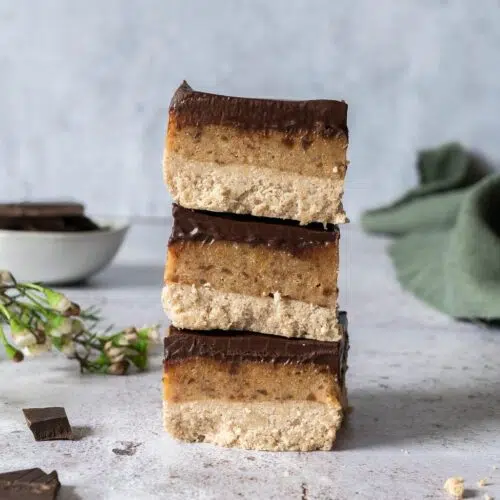 A stack of three triple layered millionaire's slices with a healthy shortbread layer, topped with date caramel and finished with rich dark chocolate
