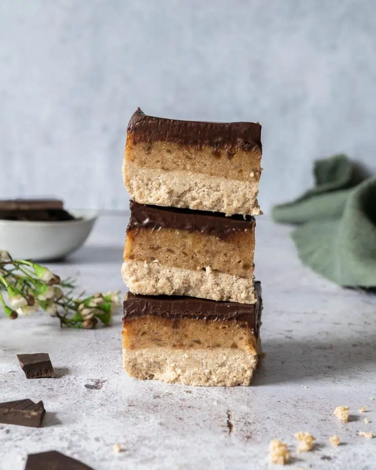 A stack of three triple layered millionaire's slices with a healthy shortbread layer, topped with date caramel and finished with rich dark chocolate