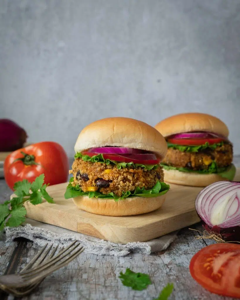 A BBQ bean burger in a soft bun, coated in a crispy breadcrumb coating and topped with lettuce, tomato and red onion.