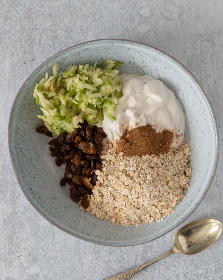 The ingredients needed to make apple Pie Bircher in a bowl ready to be stirred together
