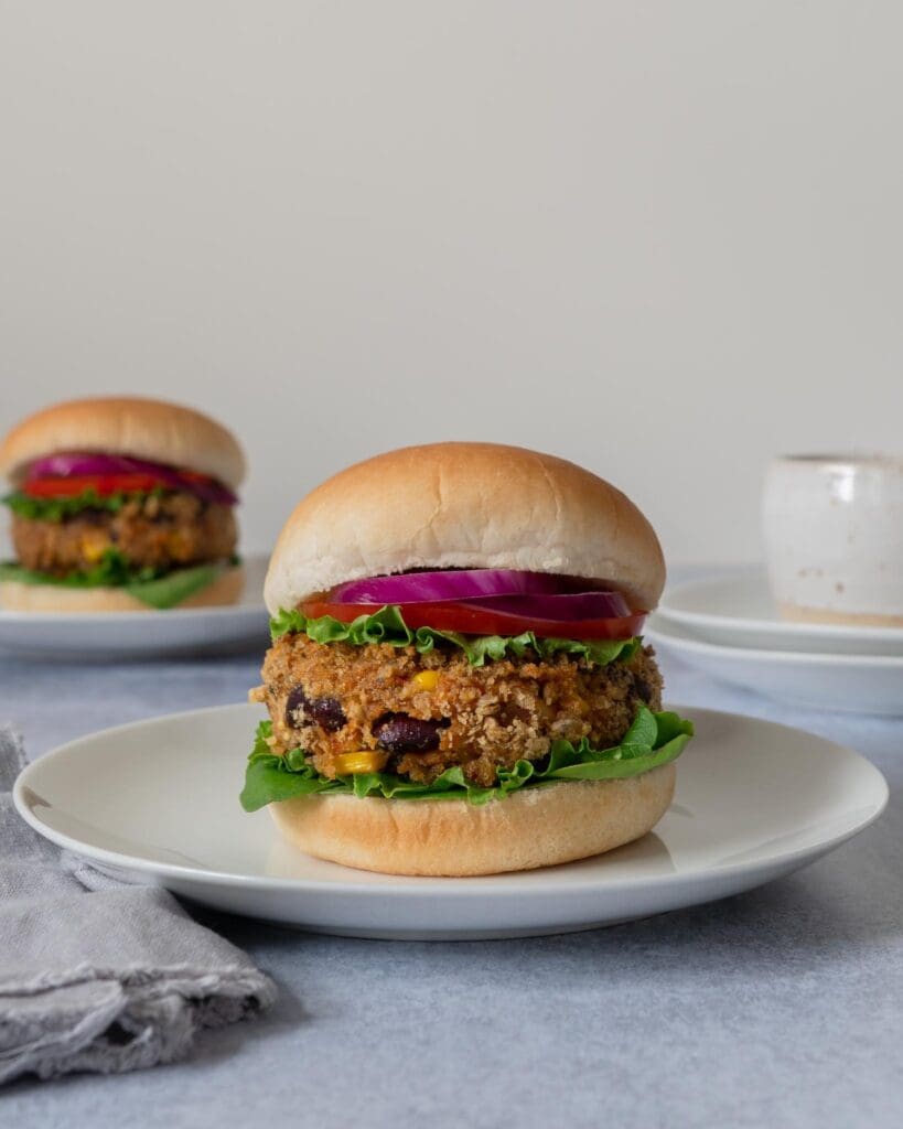 Homemade BBQ bean burgers in a crispy breadcrumb coating, in a soft bread roll with lettuce, tomato and thinly sliced red onion.