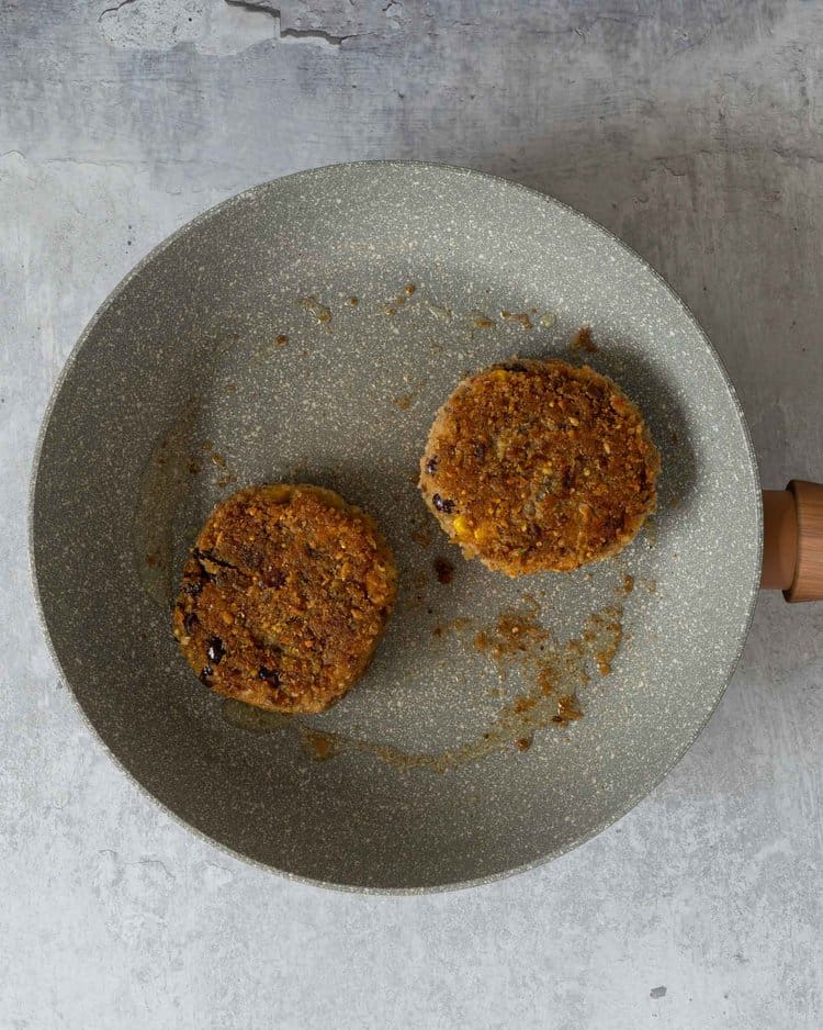 Homemade bbq bean burgers in a frying pan with a crispy breadcrumb coating