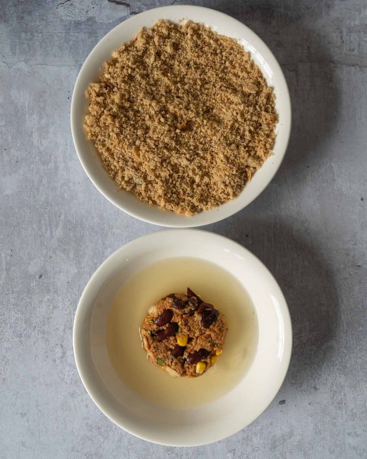 Homemade bean burgers being coated in aquafaba and breadcrumbs