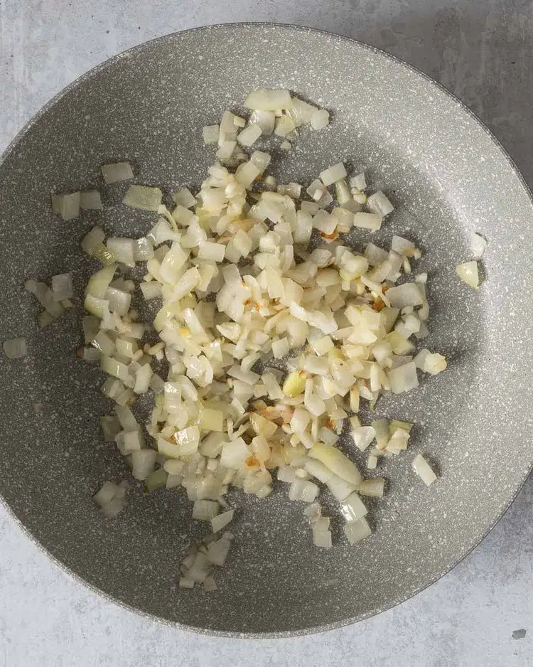 Finely diced onion being fried in a non stick pan