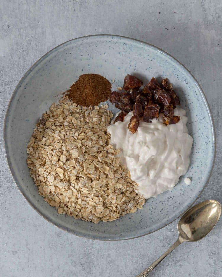 The ingredients needed to make blueberry muffin bircher in a bowl ready to be stirred