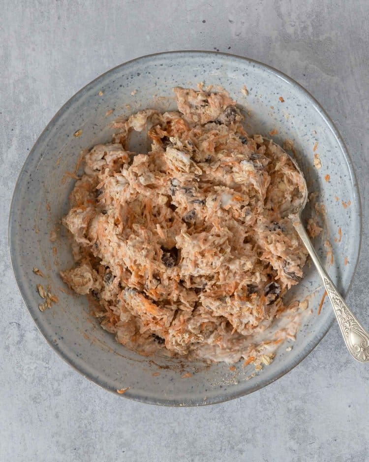 The ingredients for Carrot Cake Bircher being stirred together in a bowl