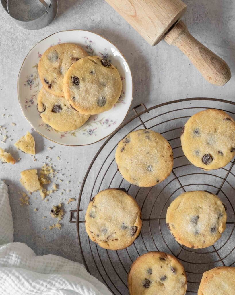 Buttery vegan chocolate chip shortbread cookies, dusted in sugar, on a cooling rack.