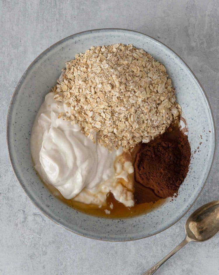 The ingredients for making chocolate peanut butter bircher in a bowl ready to be stirred together