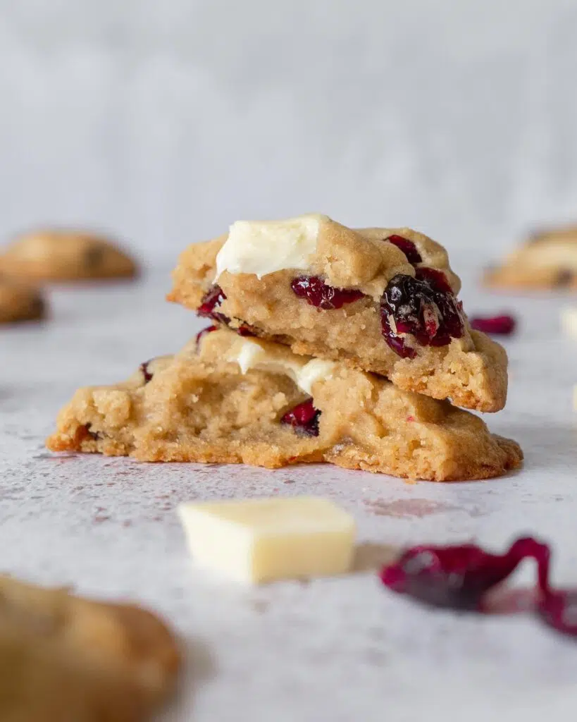 A cranberry and white chocolate cookie broken open to display a soft and chewy centre