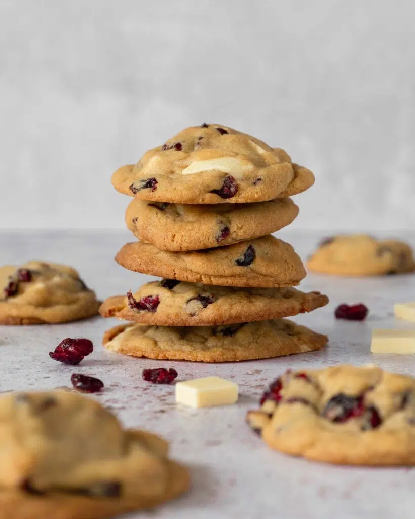 A stack of freshly baked cookies studded with vegan white chocolate pieces and tangy red cranberries