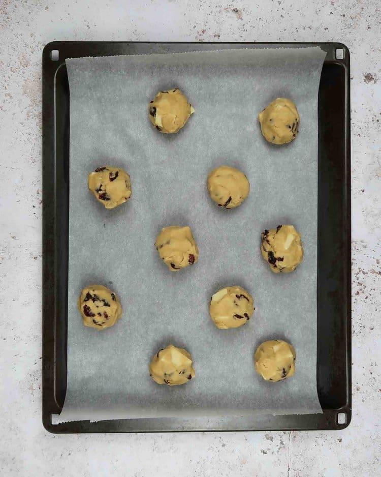 Balls of cookie dough on a lined baking tray ready to be baked