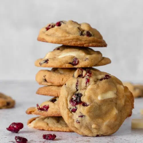 A stack of freshly baked cookies studded with vegan white chocolate pieces and tangy red cranberries