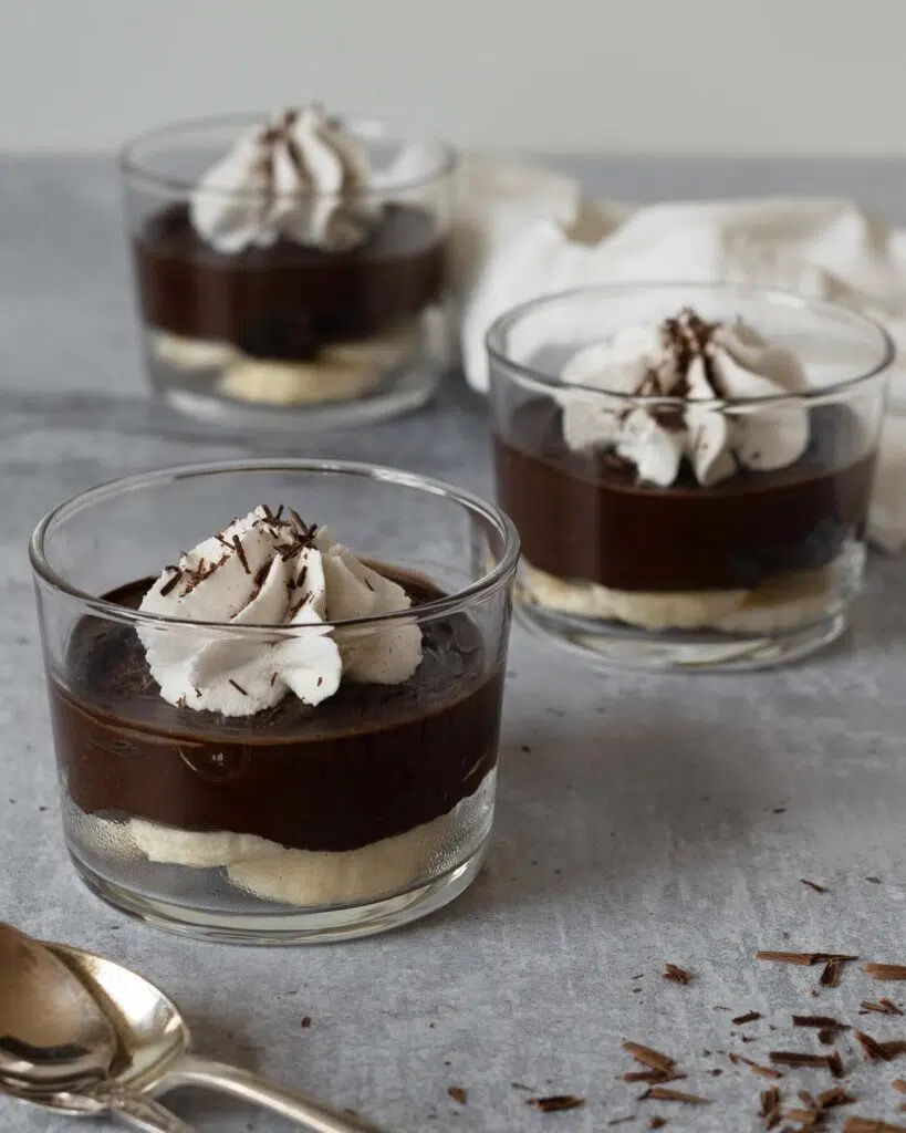 3 glass dishes of easy avocado chocolate pudding with whipped coconut cream and grated chocolate on top
