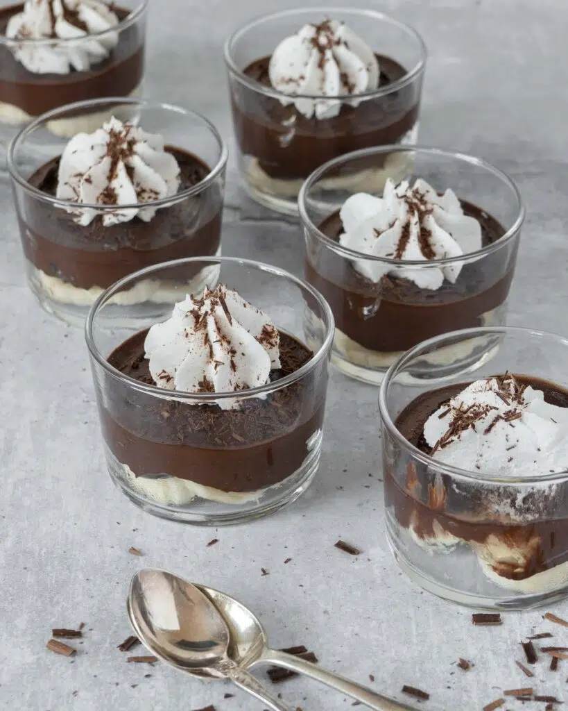 Glass dishes of easy avocado chocolate pudding with whipped coconut cream and grated chocolate on top
