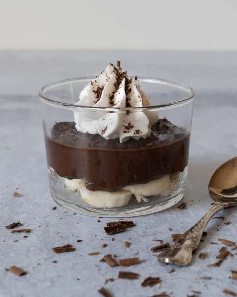 A glass dish of easy avocado chocolate pudding with whipped coconut cream and grated chocolate on top