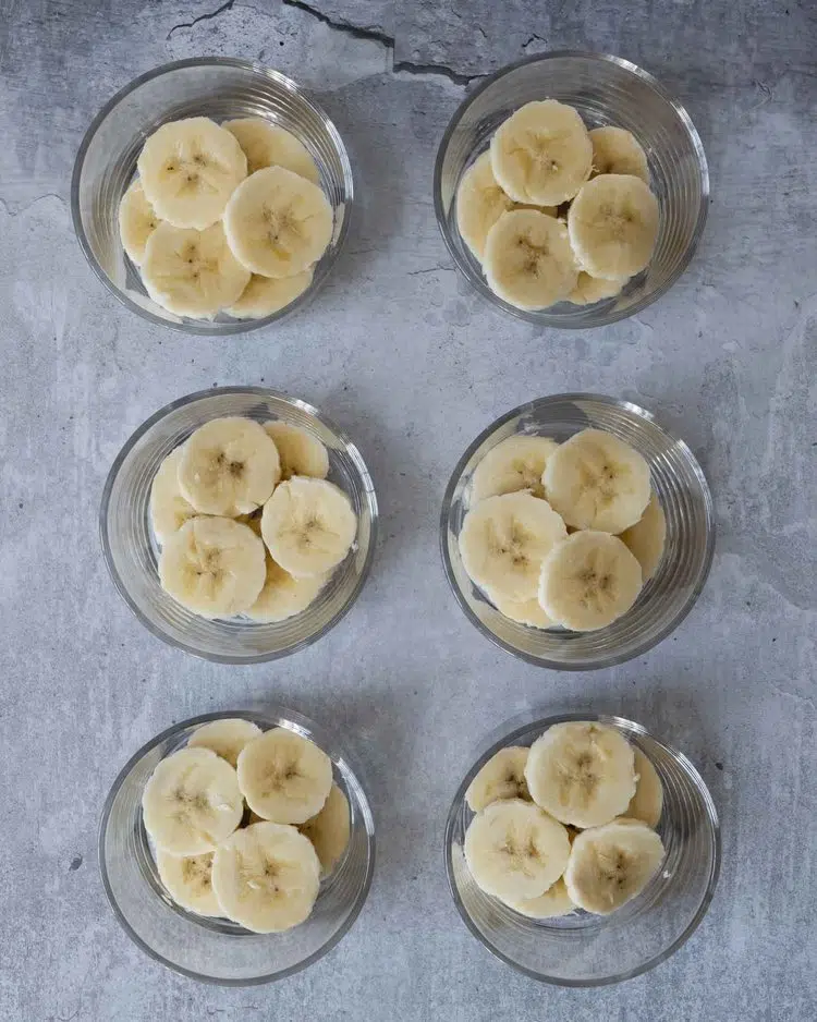 Sliced banana placed in glass dishes ready to be topped with chocolate avocado pudding