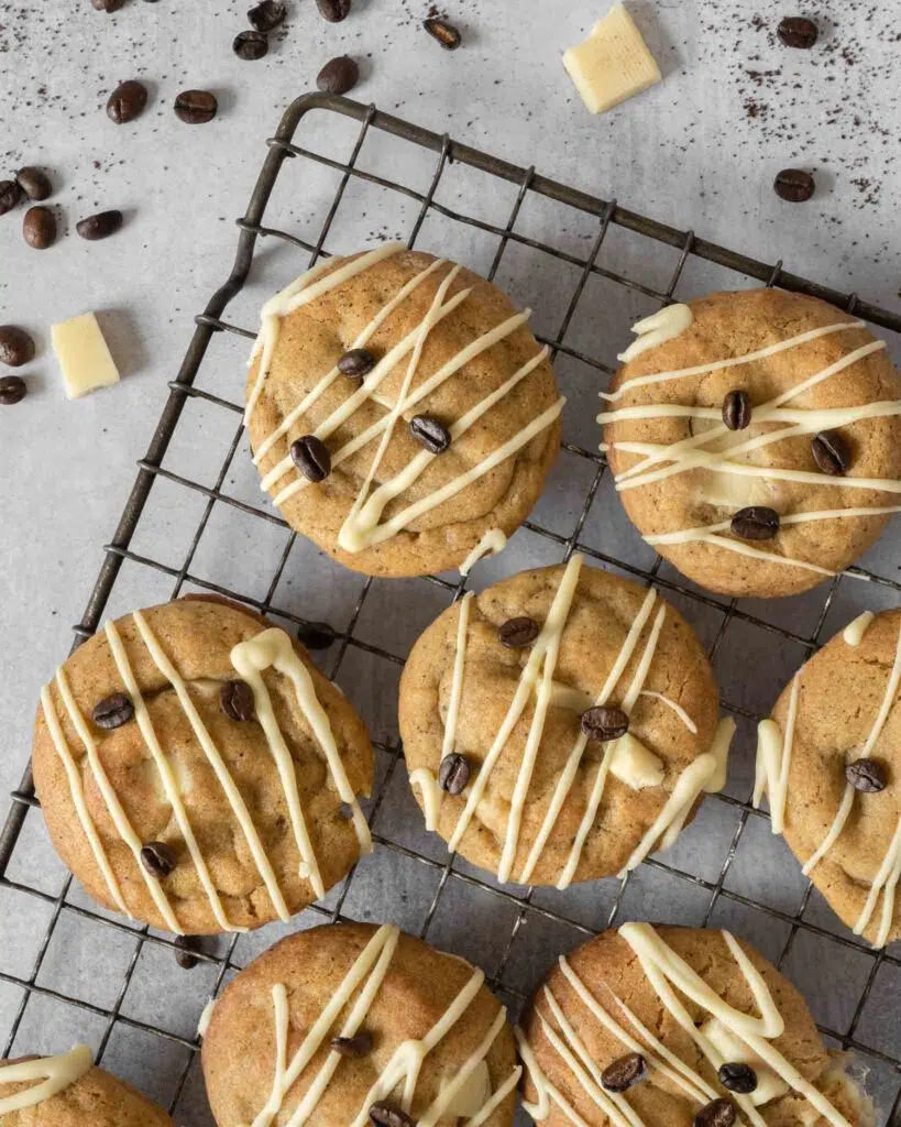 Chunky Espresso Martini Cookies laid on a cooling rack, drizzled with vegan white chocolate and decorated with coffee beans.