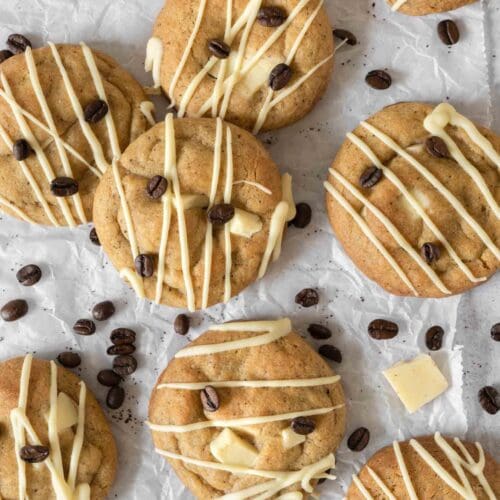 Chunky Espresso Martini Cookies laid on a table top, drizzled with vegan white chocolate and decorated with coffee beans.
