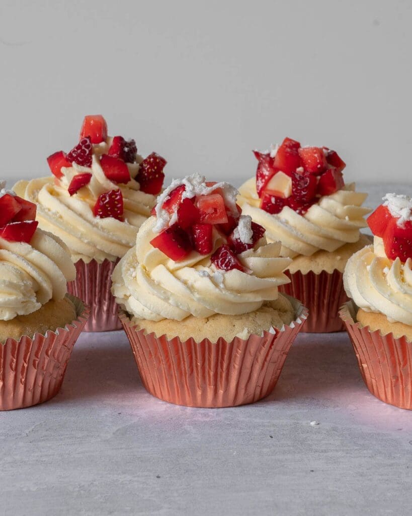 Pretty Eton Mess Cupcakes with a fluffy vanilla sponge filled with sticky strawberry jam, topped with vanilla buttercream, fresh strawberries and crumbled vegan meringue