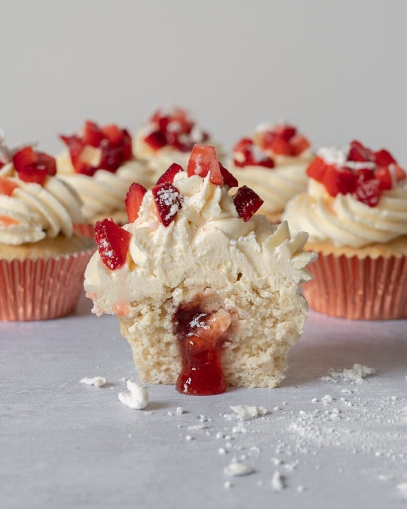 Pretty Eton Mess Cupcakes with a fluffy vanilla sponge filled with sticky strawberry jam, topped with vanilla buttercream, fresh strawberries and crumbled vegan meringue