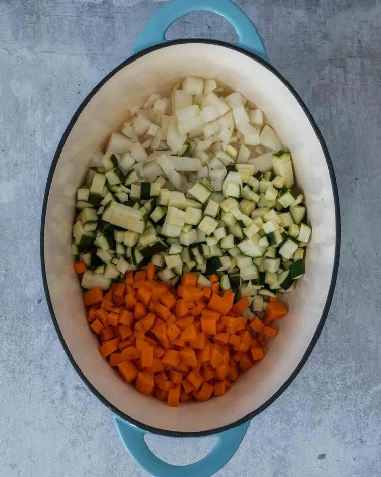Diced carrots, onion and courgette in a large saucepan ready to be gently fried
