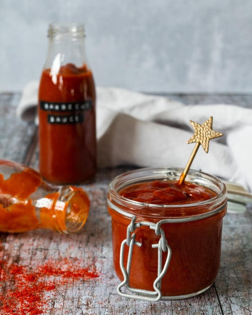 A glass jar filled with homemade BBQ sauce with a gold star spoon sticking out