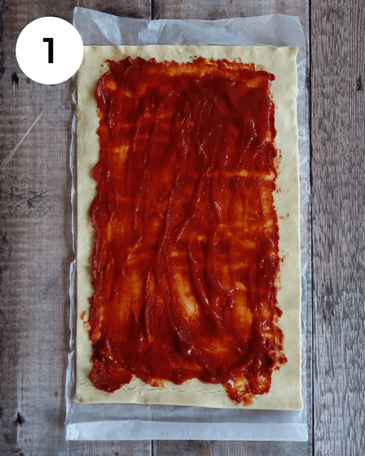 Puff pastry rolled out and topped with tomato sauce