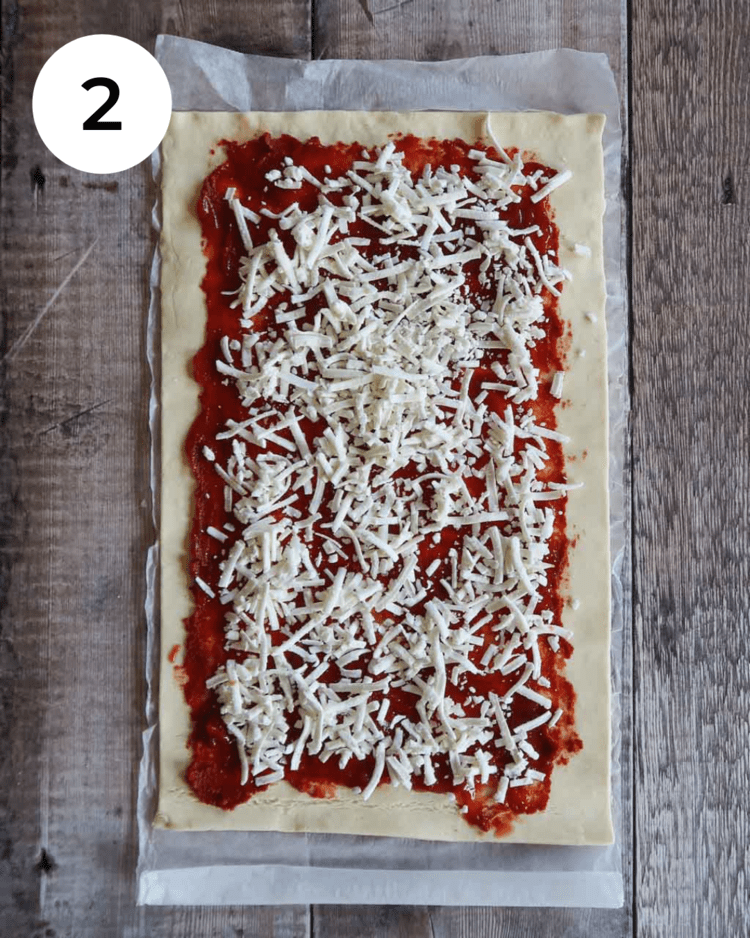 Puff pastry rolled out and topped with tomato sauce and vegan cheese