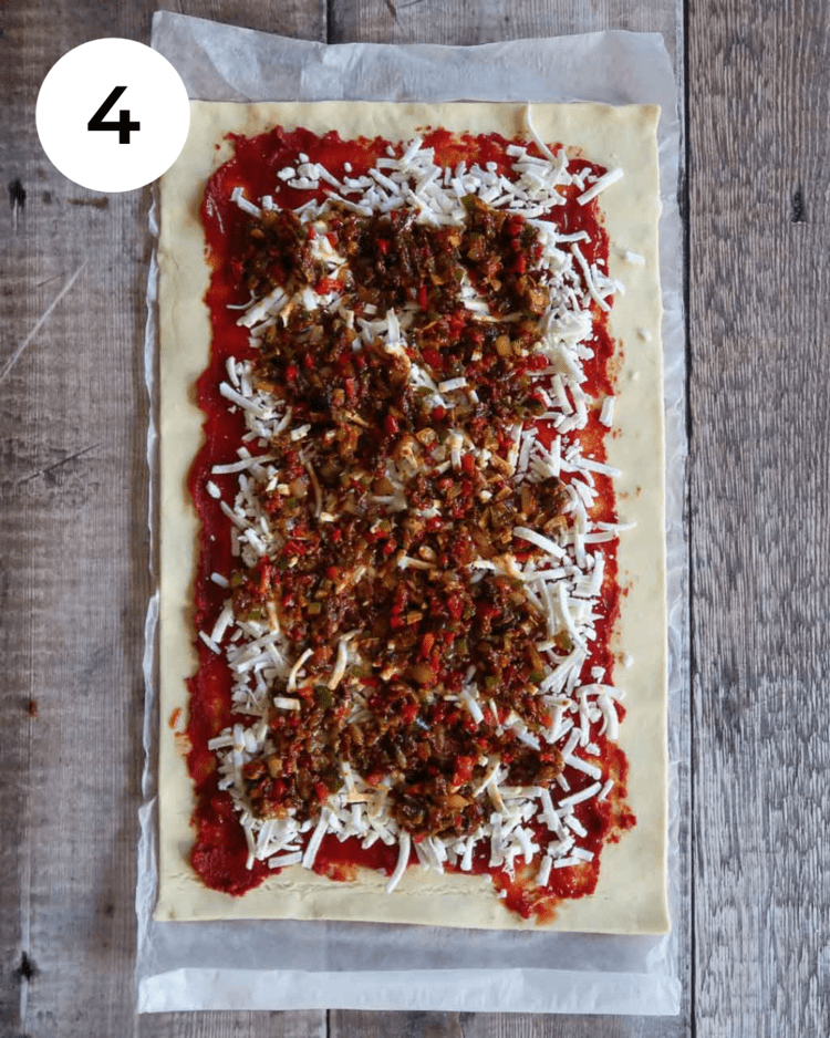 Puff pastry rolled out and topped with tomato sauce, vegan cheese and Mexican spiced vegetables