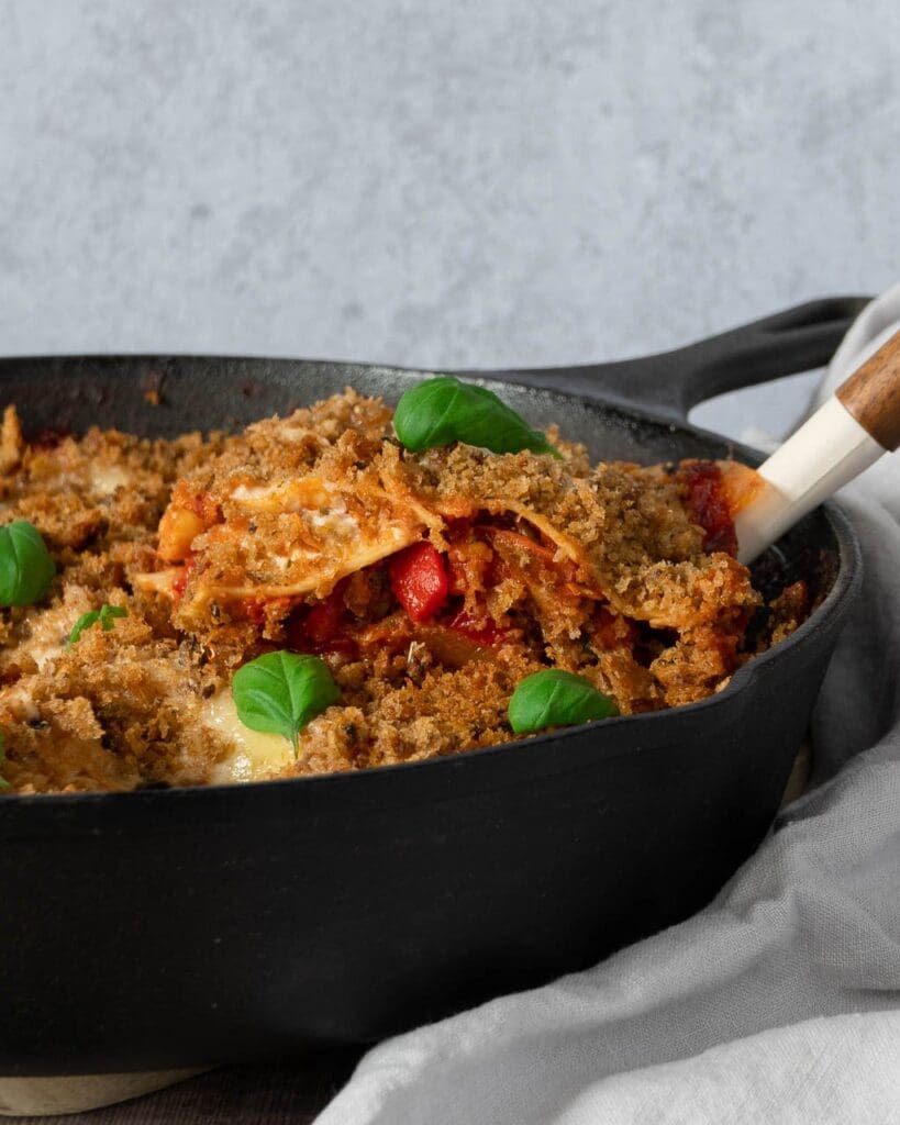 A single slice of One Pan Vegetable Lasagne being lifted out of the baking dish, with layers of pasta and colourful veggies on display.