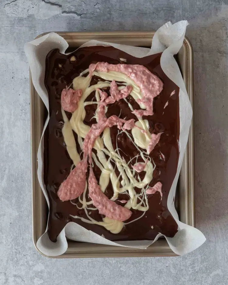 Melted dark chocolate, white chocolate and pink raspberry chocolate swirled together in a lined baking tin