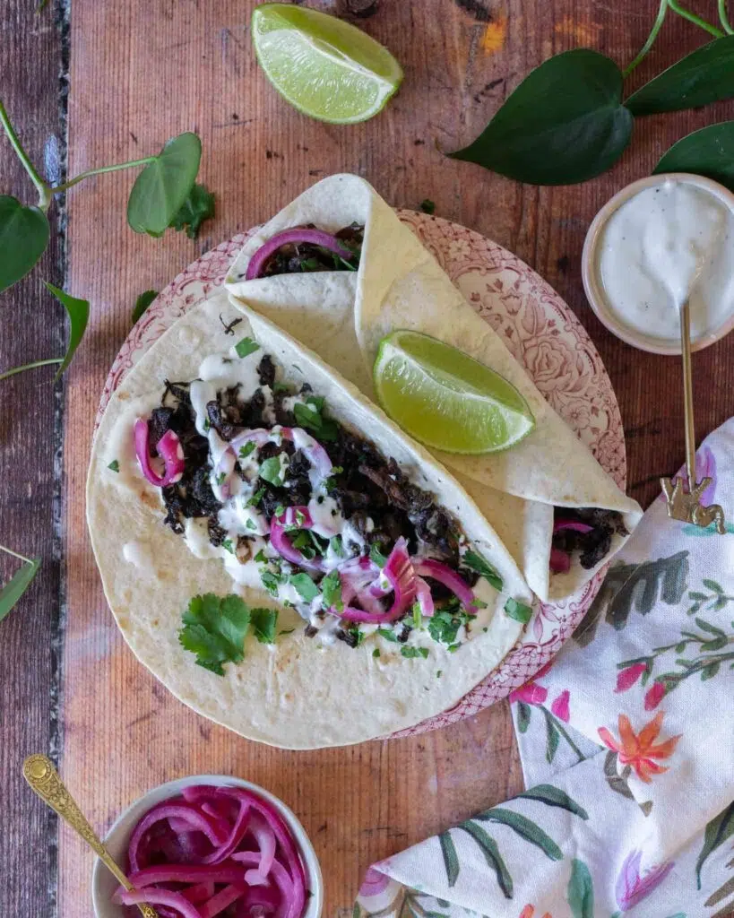 Colourful shredded mushroom carnitas in a soft tortilla with pickled red onions and fresh coriander