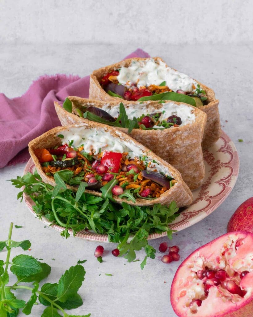 Open pitta breads stuffed with spiced shredded tofu kebab 'meat', roasted vegetables, glistening pomegranate seeds, creamy fresh tzatziki and rocket