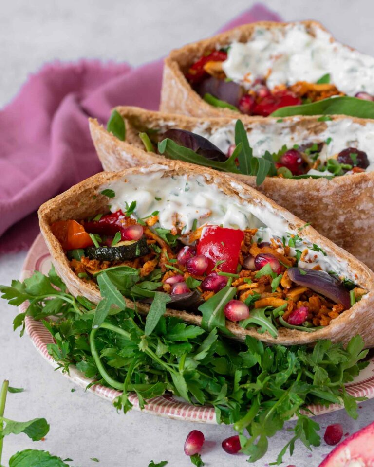 Open pitta breads stuffed with spiced shredded tofu kebab 'meat', roasted vegetables, glistening pomegranate seeds, creamy fresh tzatziki and rocket