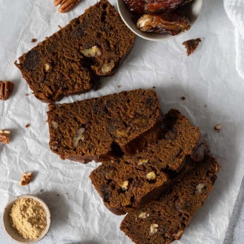 Slices of a rich sticky date cake on a table top covered with baking paper