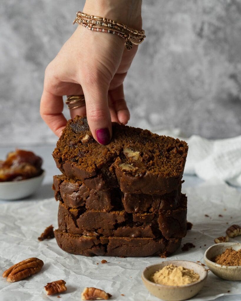 Slices of rich sticky date cake laid on top of each other, with the top one being picked up