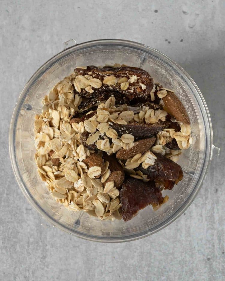 Oats, dates and almonds in a blender cup ready to be blitzed