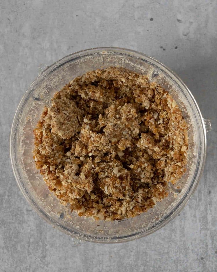 A blender cup filled with an oat, date and almond blend ready to be made into cheesecake bases