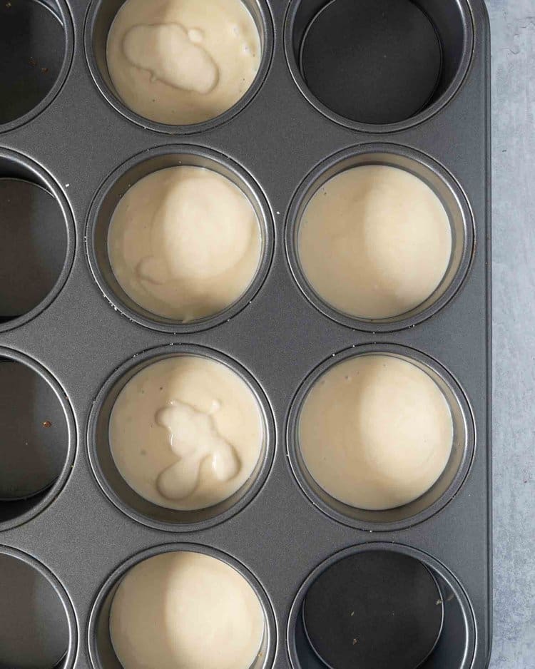 A muffin tin filled with individual mini cheesecakes