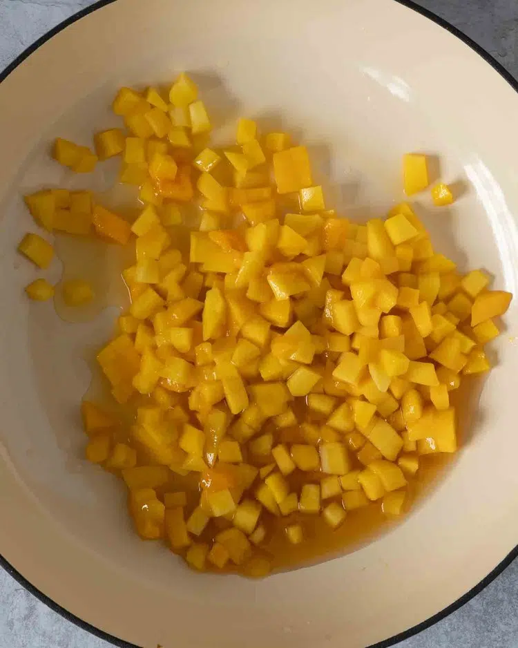 Diced mango in a frying pan with fresh lime juice and maple syrup
