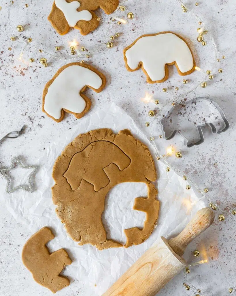 Vegan gingerbread bear biscuits laying on a white table top with fairy lights and a silver star decoration