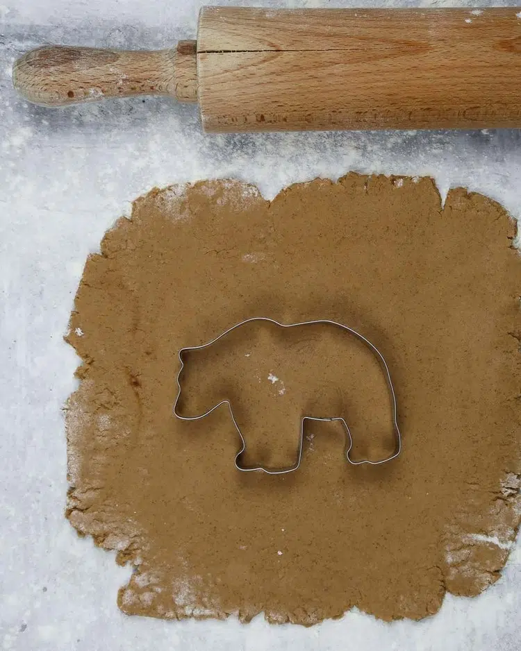 Vegan gingerbread dough rolled out with a bear shaped cookie cutter on top