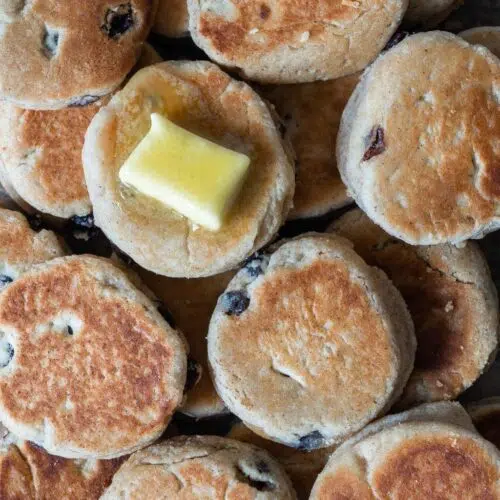 A table full of round vegan welsh cakes studded with juicy sultanas and topped with melting vegan butter