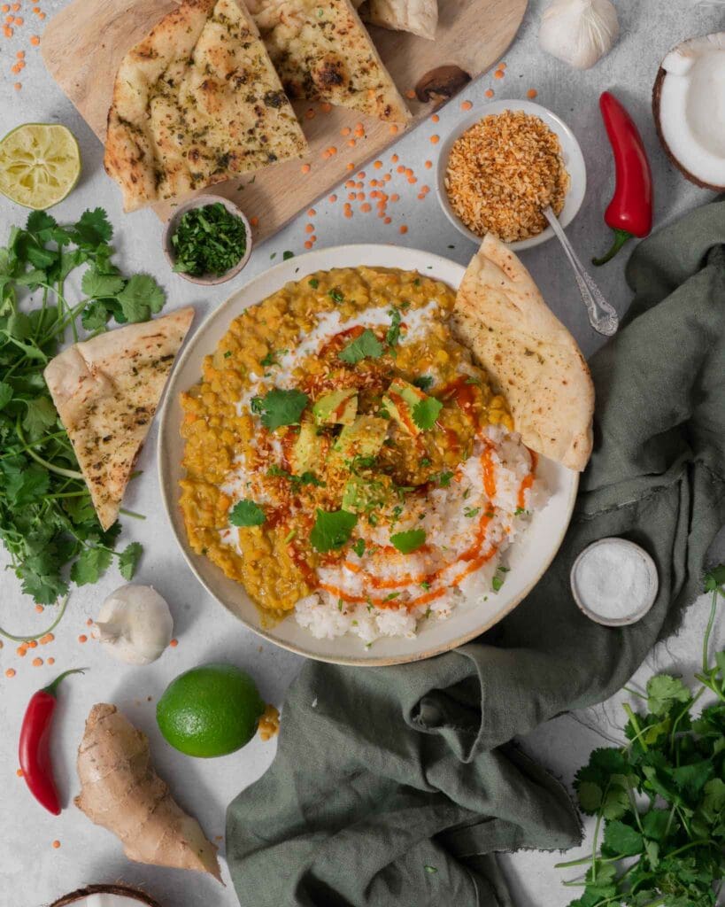 A hearty bowl of vegan red lentil dahl topped with creamy avocado, coriander and chilli sauce.
